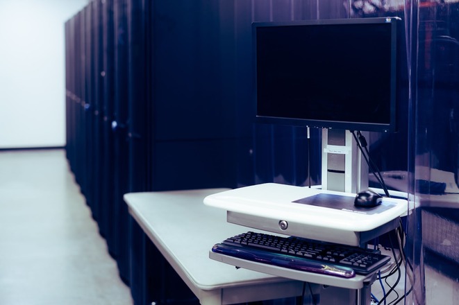 A computer next to server racks