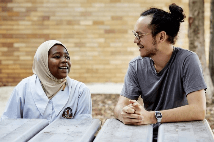 Two people from different countries talking to each other at a table